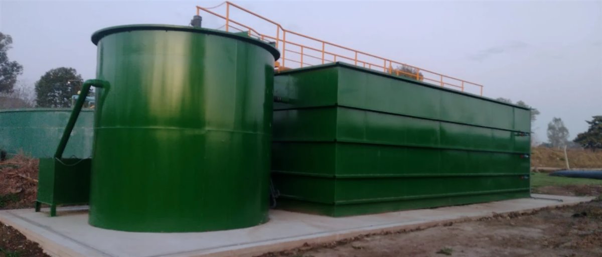 Planta de tratamiento de efluentes cloacales del barrio privado Haras de Santa María, con un reactor cilíndrico verde y un módulo rectangular con pasarela