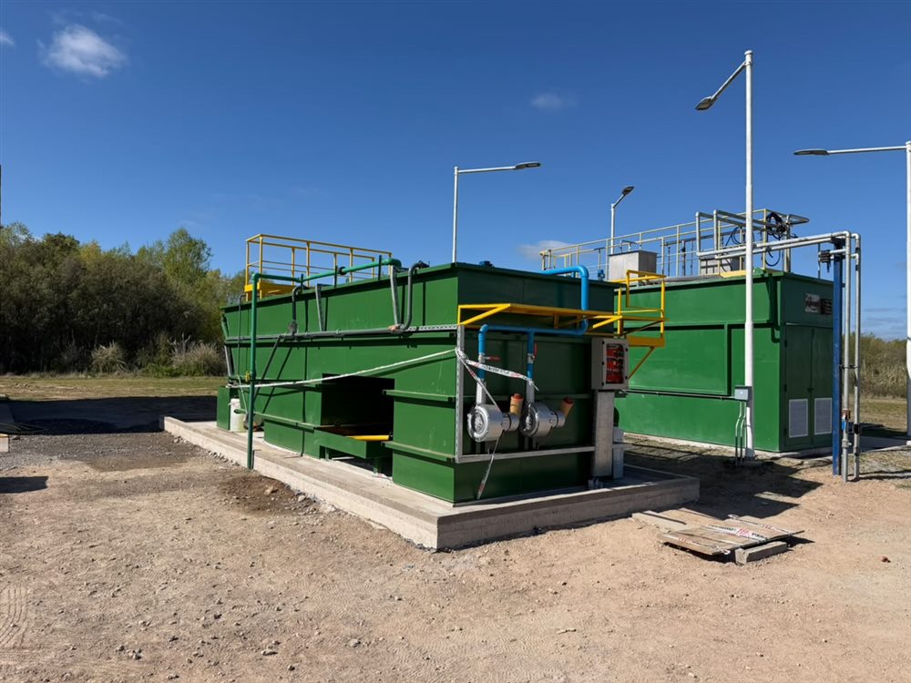 Dos módulos verdes de una planta de tratamiento de hidrocarburos, con sopladores, tablero de comando y plataformas de acceso, en un predio petrolero