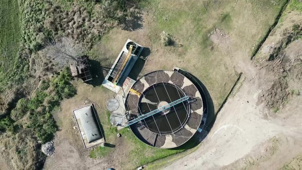 Vista aérea de una planta cloacal de barrio con su sedimentador circular, tanques y equipos