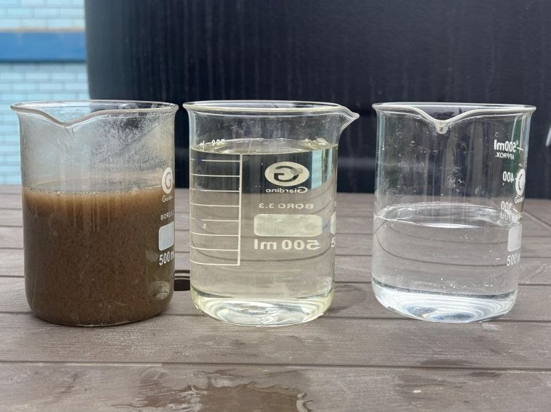 Tres vasos de laboratorio con la misma agua en distintas etapas: sin tratar, parcialmente tratada y clara