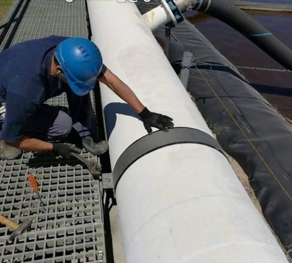 Operario colocando una abrazadera en la cañería de aire de una laguna