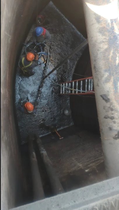 Equipo trabajando dentro de un tanque, con cadena y escalera de acceso